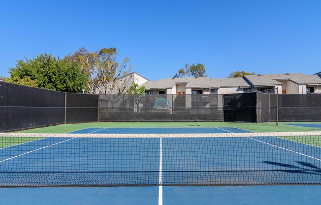 A tennis court with a blue surface and a black fence.
