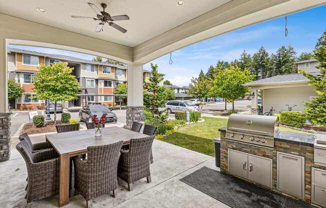 A patio with a table and chairs and a grill.