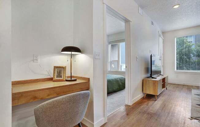A chair sits in front of a desk with a lamp and picture frame on it.