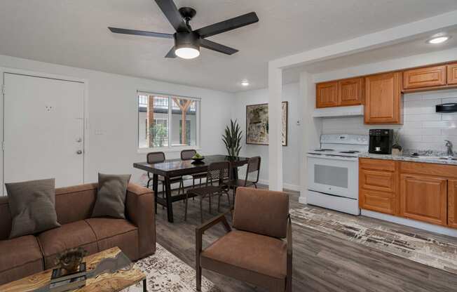 a living room and kitchen with a ceiling fan and a table with chairs