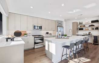 a large white kitchen with a large island and bar stools