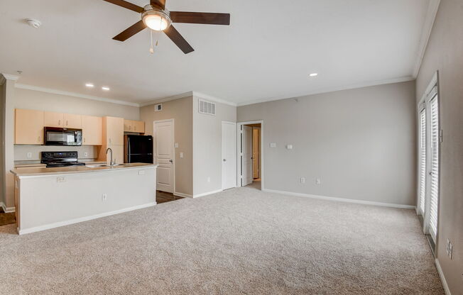 an empty living room with a ceiling fan and a kitchen at Artisan Apartments & Shops, Austin, Texas