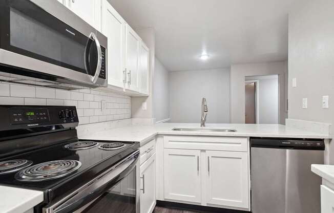 A modern kitchen with white cabinets and black appliances.