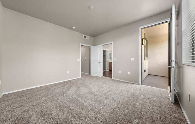 A spacious room with a carpeted floor and a doorway leading to another room.