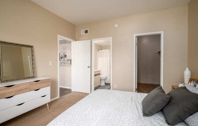a bedroom with a large bed and a mirror and a bathroom
