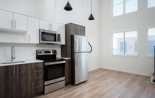 a kitchen with stainless steel appliances and white cabinets and a window