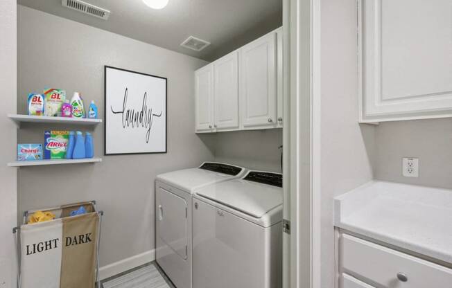 a laundry room with a washer and dryer and white cabinets