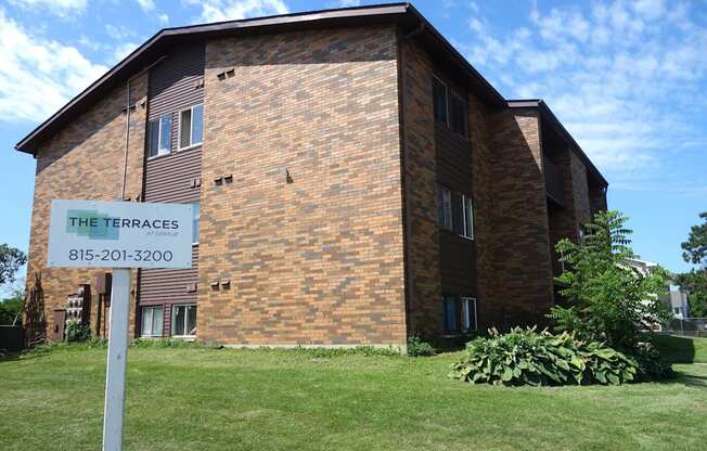 A brick building with a sign that says The Terraces and a phone number.