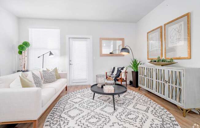 A living room with a white couch, a black and white patterned rug, and a wooden coffee table.