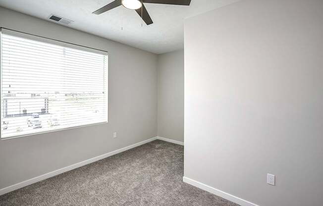 an empty room with a large window and a ceiling fan