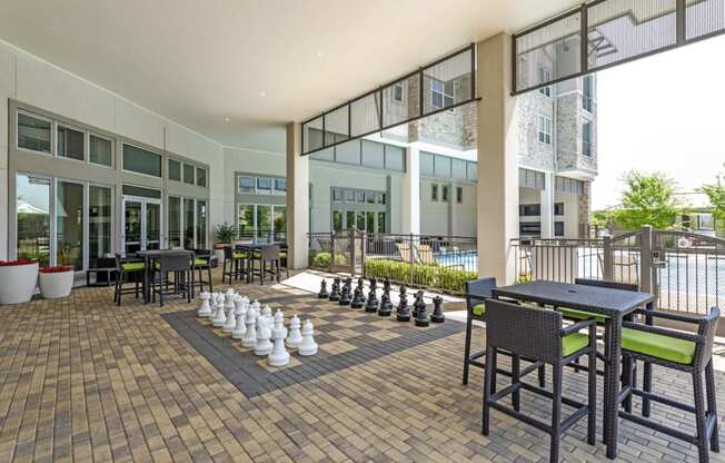 a communal patio with tables and chairs and a game of chess