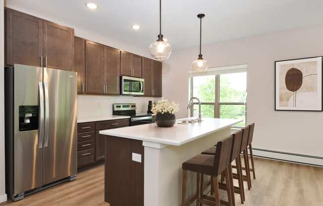 Eagan, MN Glen Pond Addition Apartments. a kitchen with wooden cabinets and a large island with a white countertop
