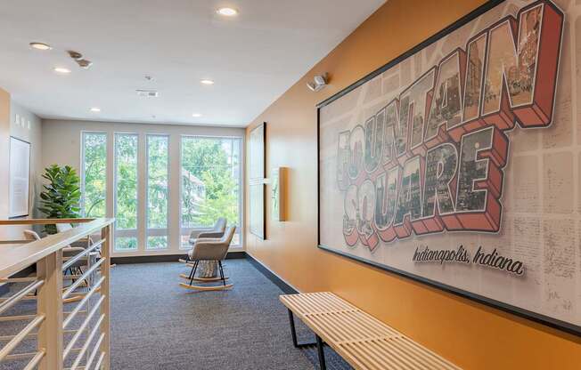A large poster with the words "Fountain Square" on it is hanging on a wall in a room with a bench and a chair.