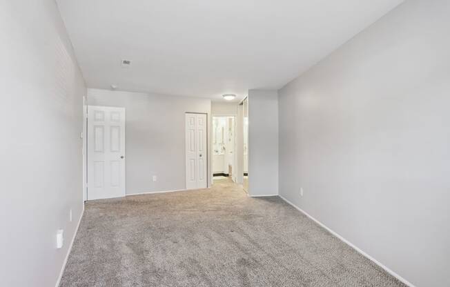 A spacious room with carpeted floor and white walls.