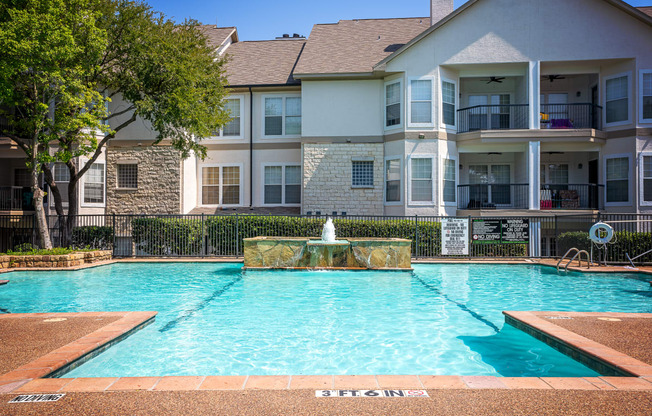 a swimming pool with a fountain in front of an apartment building