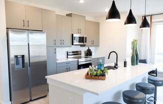 A modern kitchen with a stainless steel refrigerator and a white countertop.