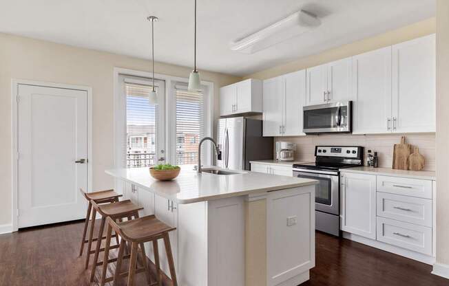 A kitchen with white cabinets and a wooden island.