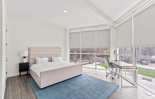 A bedroom with a large bed and a chair by the window.