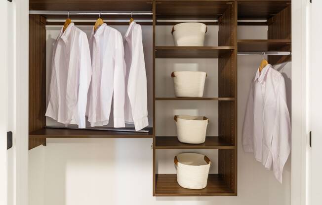 a closet with wooden shelves and baskets and white clothes at Dey & Bergen, Harrison