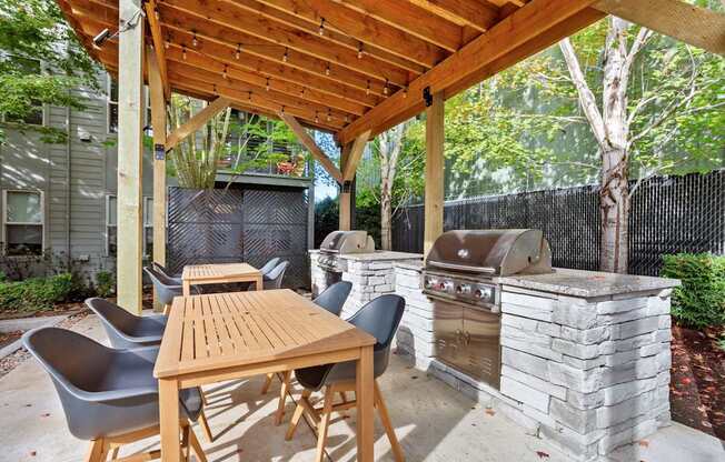 A wooden table and chairs are set up under a wooden pergola.