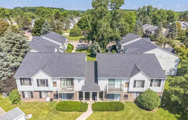 A large, two-story house with a grey roof and a balcony on the second floor.