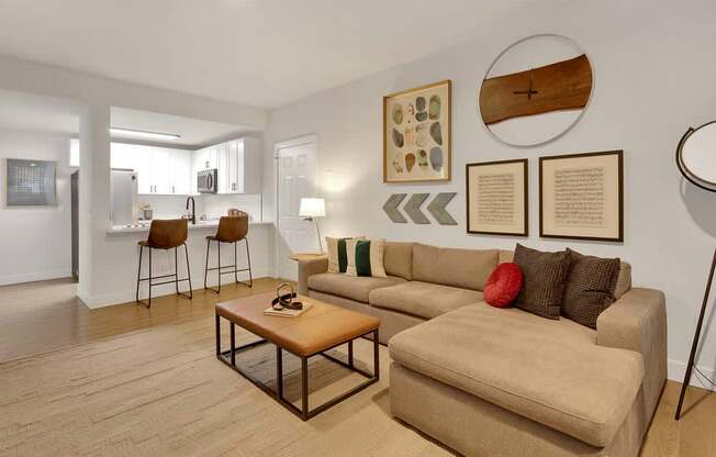 A living room with a couch, chairs, and pictures on the wall.