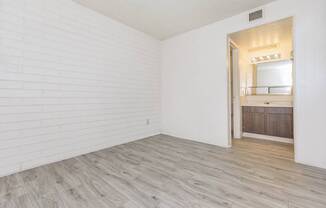 A room with a white brick wall and wooden flooring.