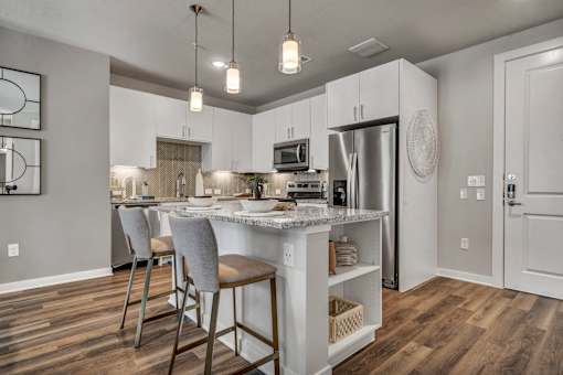 A kitchen with a white island and wooden floors.