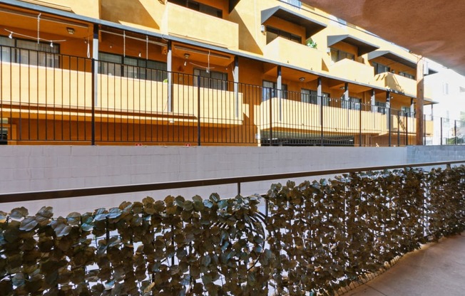 the facade of a building with a fence and a wall covered in wine bottles