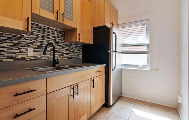 A kitchen with wooden cabinets and a black fridge.