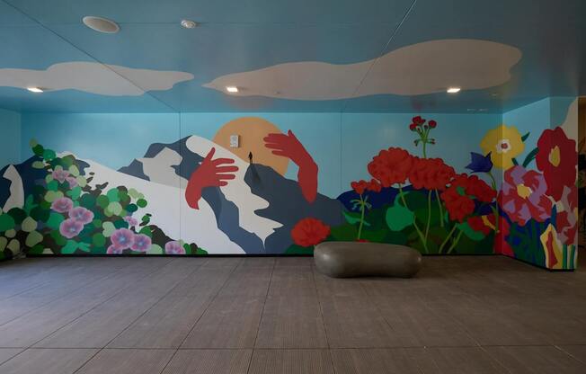 A mural of a mountain scene with a person hugging a rock is on the wall.