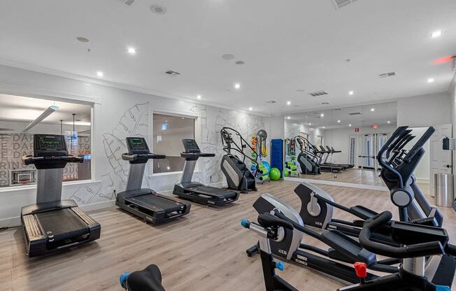 the gym has plenty of cardio equipment and a wall mural of graffiti