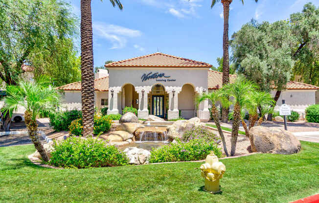 A building with a red tile roof and a sign that says "Winston's Club" is surrounded by palm trees and a garden with a waterfall.