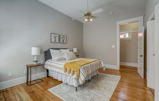 A bedroom with a bed, a lamp, and a ceiling fan.