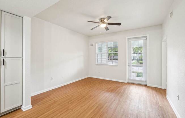 A room with a ceiling fan and wooden flooring.