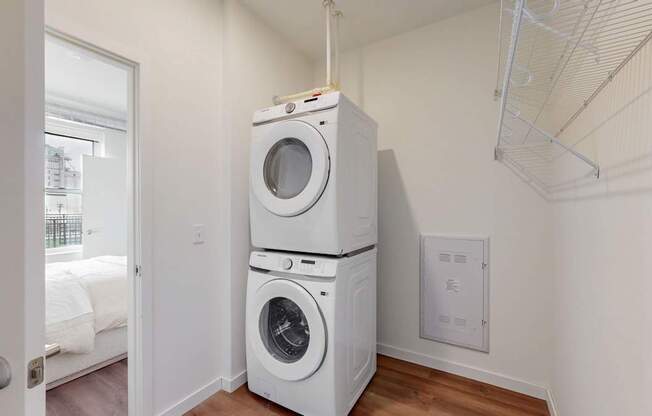 A white dryer and washer stacked on top of each other in a laundry room.