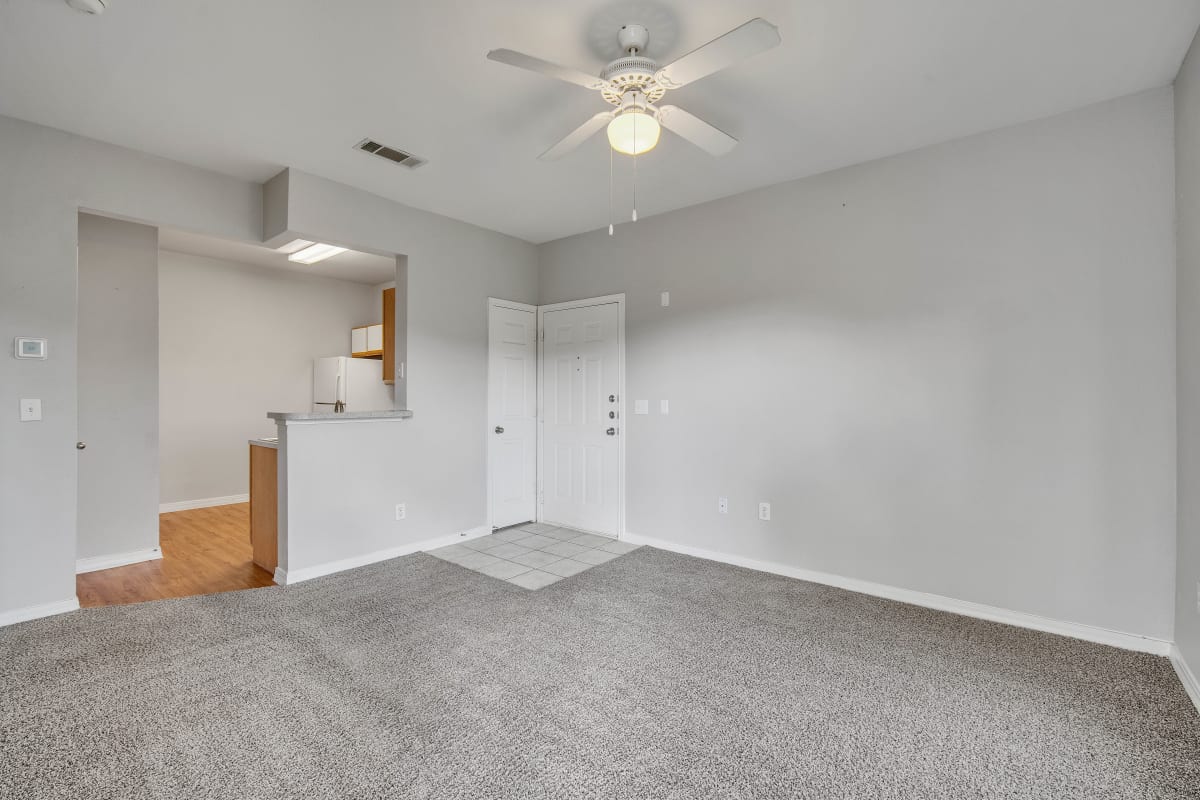 an empty living room with carpet and a ceiling fan