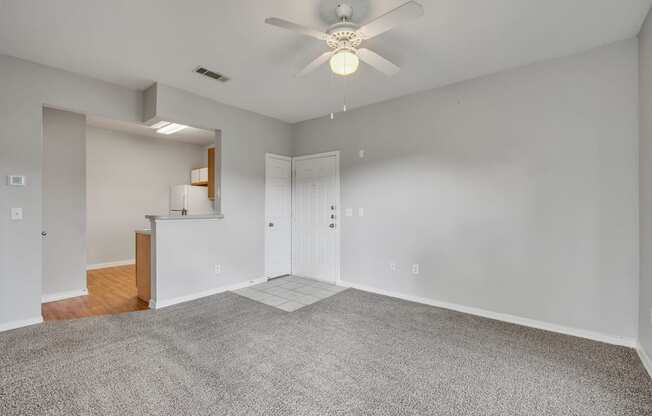 an empty living room with carpet and a ceiling fan