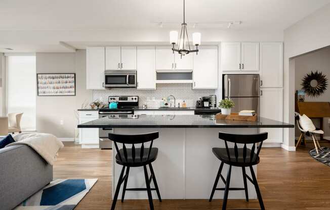 a kitchen with white cabinets and a counter with two bar stools