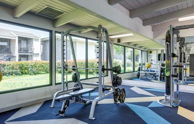 A gym with a view of apartment buildings outside the window.