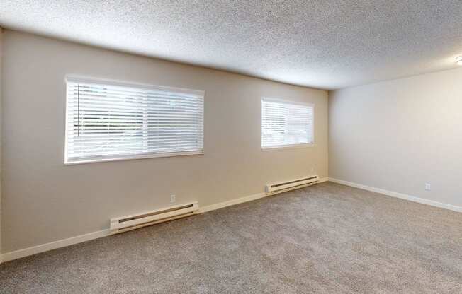 Bright one-bedroom layout at Peak 88 Apartments Renton with two windows allowing natural light and plush carpeting.