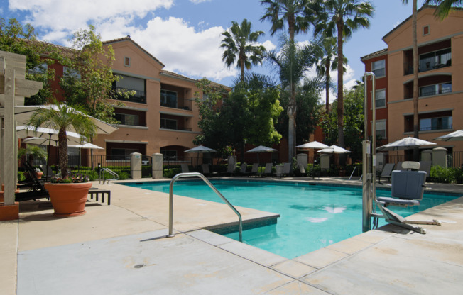 A swimming pool surrounded by palm trees and chairs.