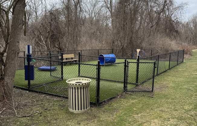 A fenced area with a blue object and a trash can.