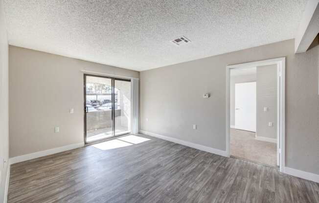 an empty living room with a sliding glass door to a patio