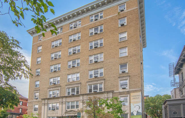 a tall brick building with many windows and a street in front