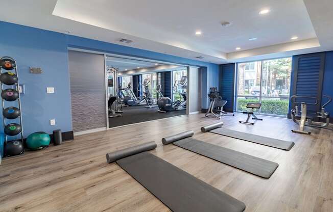 a gym with yoga mats and exercise equipment on a wood floor