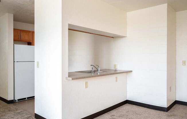 an empty kitchen with a sink and a refrigerator