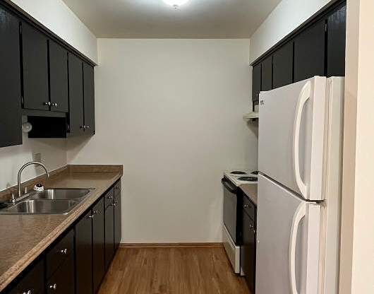 A kitchen with black cabinets and a white fridge.