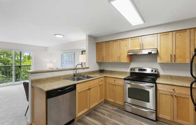 a kitchen with wooden cabinets and stainless steel appliances at Villaggio Apartment Homes, Tacoma, 98402