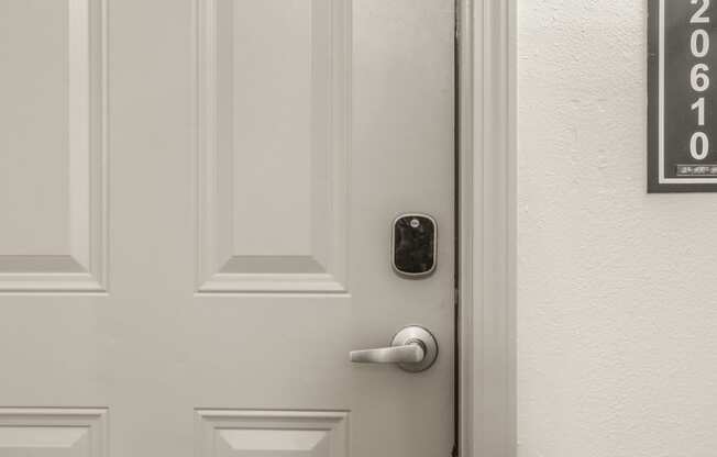 a white door with a black door handle and a white wall with a door number